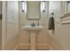Elegant half bath with a pedestal sink, decorative mirror, and traditional wainscoting at 907 Eden Se Ave, Atlanta, GA 30316