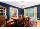 Elegant dining room featuring dark blue walls, hardwood floors, a large wooden table with chairs, and a stylish chandelier at 2960 Cedar Knoll Dr, Roswell, GA 30076