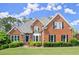 Traditional brick home featuring a manicured lawn, mature landscaping, and a symmetrical facade with classic architectural details at 13090 Magnolia Crescent Dr, Roswell, GA 30075