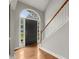 Bright foyer featuring hardwood floors, a staircase with white railings, and a black front door with sidelights at 13090 Magnolia Crescent Dr, Roswell, GA 30075
