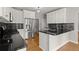 Stylish kitchen features granite countertops, stainless steel appliances, white cabinets, and hardwood floors at 13090 Magnolia Crescent Dr, Roswell, GA 30075