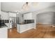 Open kitchen view with stainless steel appliances, white cabinetry, granite counters, and hardwood flooring at 13090 Magnolia Crescent Dr, Roswell, GA 30075