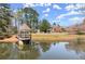 Beautiful waterfront home with a pond, gazebo, covered benches and blooming trees offering a serene view at 13090 Magnolia Crescent Dr, Roswell, GA 30075