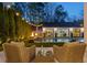 Cozy outdoor seating overlooking a luxurious pool and stylish pool house, illuminated by charming string lights at 7165 Cordery Rd, Cumming, GA 30040