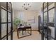 A home office with a modern desk, black-framed French doors, and a neutral color palette at 7165 Cordery Rd, Cumming, GA 30040