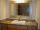 This bathroom includes a granite countertop, a large framed mirror and wood cabinets at 219 Park Avenue, Woodstock, GA 30188