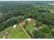 Aerial view of a modern home on a wooded lot near a lake, with outbuildings and a long driveway at 5210 Brownlee Rd, Stone Mountain, GA 30087