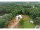 Aerial view of a unique modern home, surrounded by lush greenery, a pond, and outbuildings at 5210 Brownlee Rd, Stone Mountain, GA 30087
