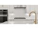 The kitchen features a tile backsplash, stainless steel hood, quartz countertops, and gold hardware at 1659 Tielman Way, Snellville, GA 30078