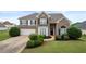 Beautifully landscaped home featuring a manicured lawn, brick facade, and attached garage at 2127 Grant Ave, Mcdonough, GA 30252