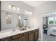 Bathroom featuring double sink, quartz countertops, large mirror, and view into the main bedroom at 248 Nesta Grove, Locust Grove, GA 30248
