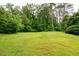 Open backyard with lush green grass and mature trees providing ample shade at 2808 Peeler Rd, Dunwoody, GA 30360
