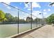 Well-maintained community tennis court with a green surface, surrounded by a high fence and lush greenery at 3750 Maryhill Nw Ln, Kennesaw, GA 30152