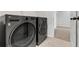 A modern laundry room featuring a gray washer and dryer with ceramic tile flooring and storage space at 776 Clifftop Xing Xing, Powder Springs, GA 30127