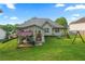 Large, grassy backyard featuring a patio, covered structure, mature trees, and play equipment at 107 Hearthstone Walk, Woodstock, GA 30189