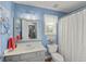 Light blue bathroom with vanity, toilet, shower with curtain and colorful decor at 107 Hearthstone Walk, Woodstock, GA 30189