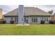 Back exterior featuring a patio, green lawn, mature bushes and a chimney at 231 Yardsley Dr, Mcdonough, GA 30253
