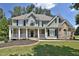 Charming two-story home with a manicured lawn, inviting front porch, and stone accents at 6425 Riley Manor Way, Cumming, GA 30028