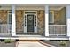 Charming front porch with stone columns, a decorative wreath on the front door, and neat landscaping at 6425 Riley Manor Way, Cumming, GA 30028