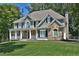 Beautiful exterior featuring a covered front porch, mixed siding, stone accents, and manicured lawn at 6425 Riley Manor Way, Cumming, GA 30028