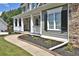 Inviting front porch of a home with stone accents, white columns, and manicured landscaping at 6425 Riley Manor Way, Cumming, GA 30028