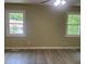 Bright bedroom featuring hardwood floors, two windows with natural light, and a ceiling fan at 5950 Wintergreen Rd, Norcross, GA 30093