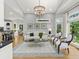 Bright living room with hardwood floors, white furniture, chandelier, and picture windows at 9745 Autry Falls Dr, Alpharetta, GA 30022