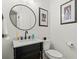 Stylish powder room featuring a modern vanity, round mirror, and framed artwork at 9745 Autry Falls Dr, Alpharetta, GA 30022