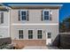 A rear view of a charming townhome featuring gray siding, a brick foundation, and a well-lit doorway at 154 Bluffington Way, Marietta, GA 30066