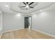 Large bedroom with tray ceiling, ceiling fan, and light-colored wood flooring at 11020 Knotty Pine Pl, Hampton, GA 30228