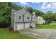 View of house featuring gray siding, a driveway, and surrounded by lush greenery at 11020 Knotty Pine Pl, Hampton, GA 30228