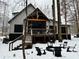 Backyard of home with snow, including a covered deck, fire pit and wooded surroundings at 1544 Bullard Rd, Powder Springs, GA 30127
