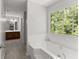Bright bathroom featuring a soaking tub with garden view and a vanity with wood cabinets at 130 Timber Oak Cv, Lawrenceville, GA 30043