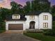 Twilight view of elegant home featuring a manicured lawn, mature trees, and inviting entrance at 130 Timber Oak Cv, Lawrenceville, GA 30043