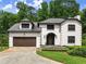 Elegant two-story home with a brown garage door, manicured lawn, and mature trees at 130 Timber Oak Cv, Lawrenceville, GA 30043