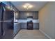 Galley kitchen features gray cabinets, black appliances, and tile backsplash at 2066 Tidwell Trl, Stone Mountain, GA 30088