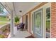 Cozy front porch with seating, brick columns, and a patterned glass front door at 2005 Ashton Pointe Dr, Dacula, GA 30019