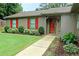 Close up on a charming single-story home featuring a stone accent wall, a red door, and a well-manicured lawn at 199 Candy Ln, Canton, GA 30115