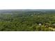Scenic aerial shot of tree-lined property showcasing natural beauty, home, and distant cityscape at 2216 Trammel Rd, Cumming, GA 30041