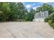 Wide driveway with a basketball hoop and a two-car garage surrounded by lush greenery at 2216 Trammel Rd, Cumming, GA 30041