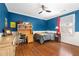 Blue bedroom with hardwood floors, a ceiling fan, built in desk, and desk at 8643 Ellard Dr, Alpharetta, GA 30022