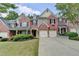 Lovely exterior view of a brick townhome featuring a two-car garage and green landscaping at 1102 Lexington Dr, Roswell, GA 30075