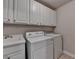 Bright laundry room features ample storage cabinets, sink, washer, and dryer at 1102 Lexington Dr, Roswell, GA 30075