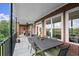 Covered brick balcony with seating and dining space and wooded views at 3330 Overland Dr, Roswell, GA 30075