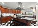 A kitchen with black countertops, wood cabinets, a gas stovetop island, stainless steel appliances, and a checkerboard floor at 3330 Overland Dr, Roswell, GA 30075