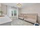 Bedroom with two cribs, bright window, a patterned rug, and modern lighting fixture at 530 Camber Woods Dr, Roswell, GA 30076