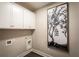 Convenient laundry room with built-in white cabinets and a modern artistic touch to elevate the space at 3351 Orwell Way # 2304, Cumming, GA 30041