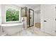Bright and modern bathroom with a stand-alone tub, black framed shower and a large window at 3684 Clearbrooke Way, Duluth, GA 30097