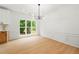 Bright dining room with a modern chandelier, large window, wood floors, and painted wainscotting at 3684 Clearbrooke Way, Duluth, GA 30097