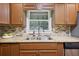 Granite countertops and stainless sink create a functional kitchen space with window view and tile backsplash at 2383 Edgewater Sw Dr, Atlanta, GA 30311